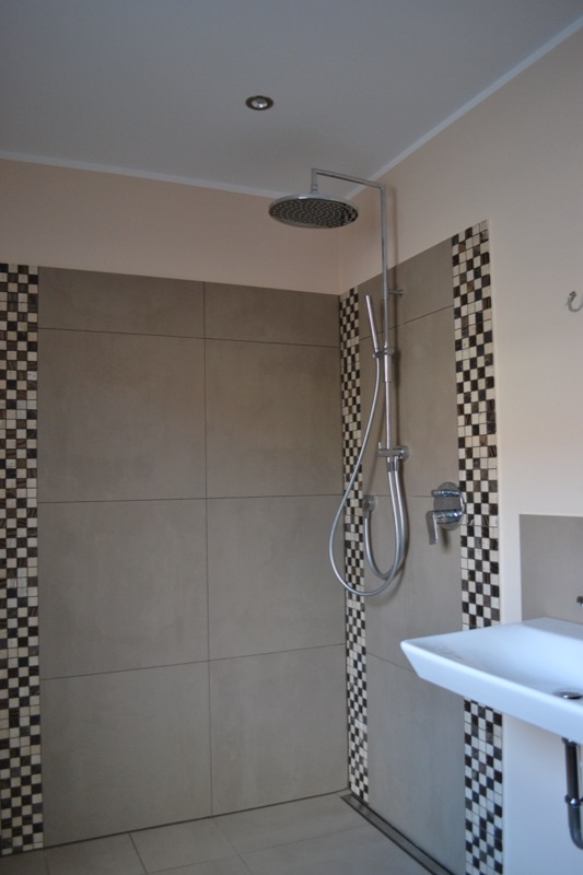 Bad mit bodengleicher Regendusche, großformatigen Fliesen und Mosaikbändern