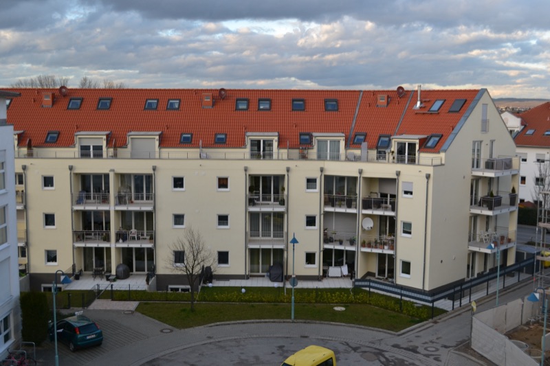 Fertiggestellte Wohnanlage mit heller Putzfassade, Loggien und rotem Ziegeldach